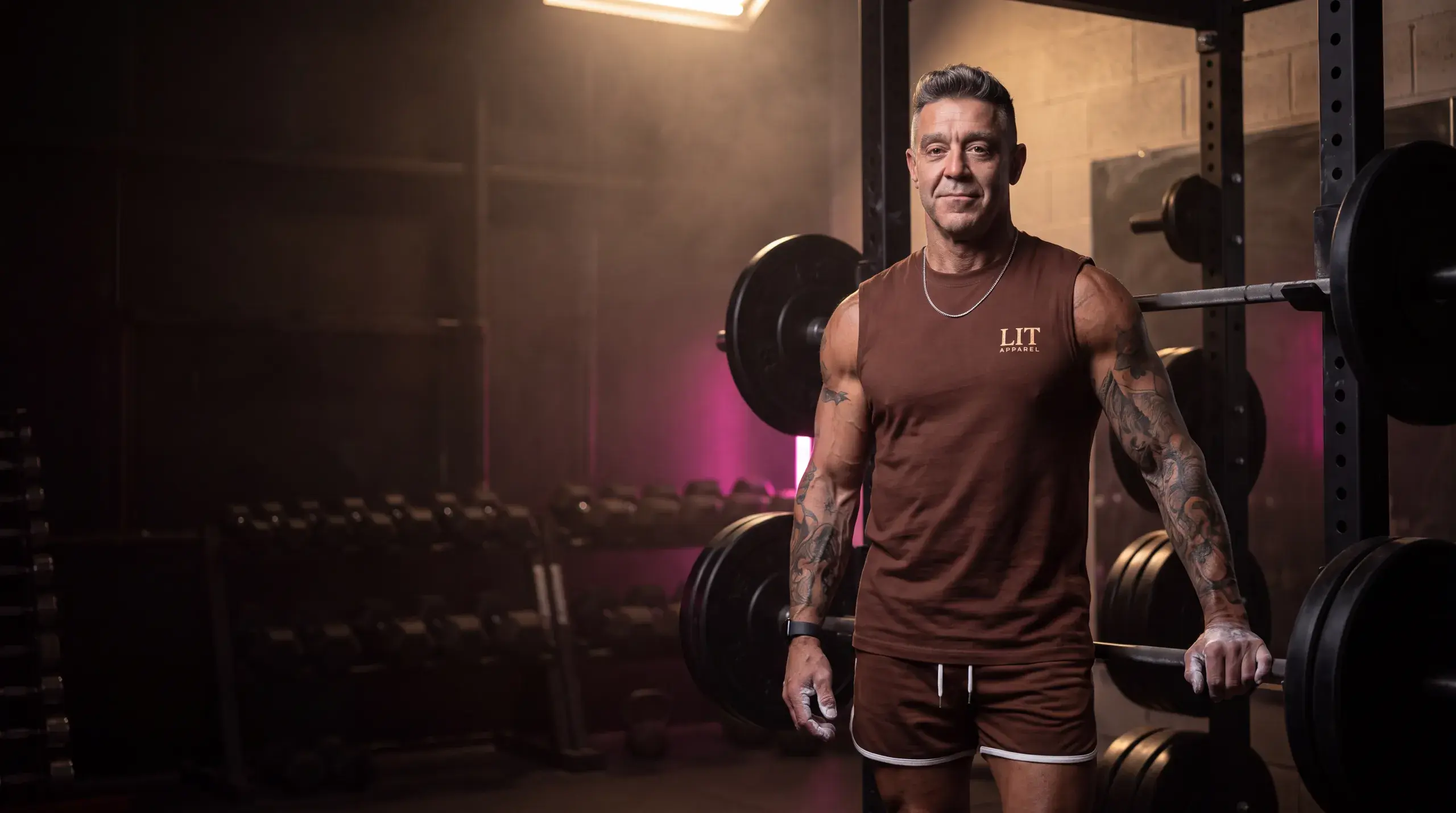 Kory in a LIT tank beside a loaded barbell in the gym