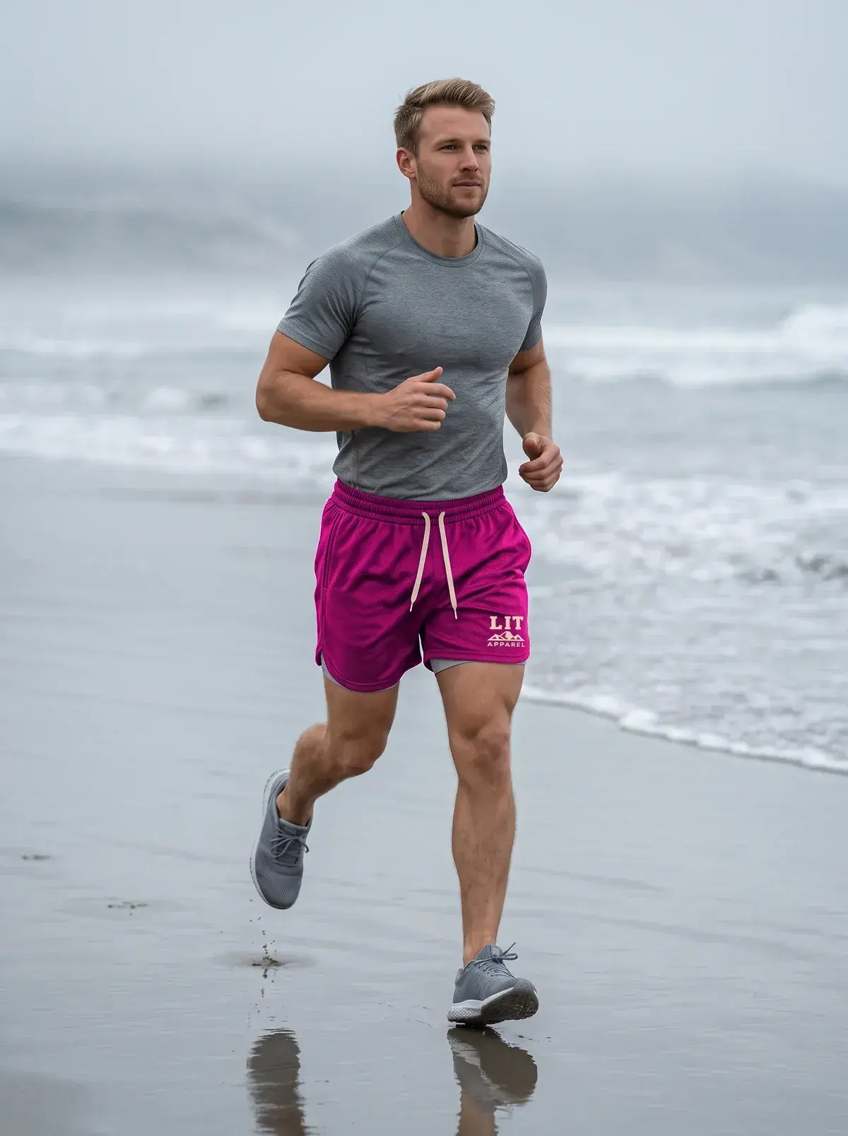 A man in a grey tee and pink mesh shorts runs along the edge of the sea.